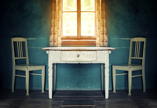 old  vintage room with table and two chairs and sun shining through the window