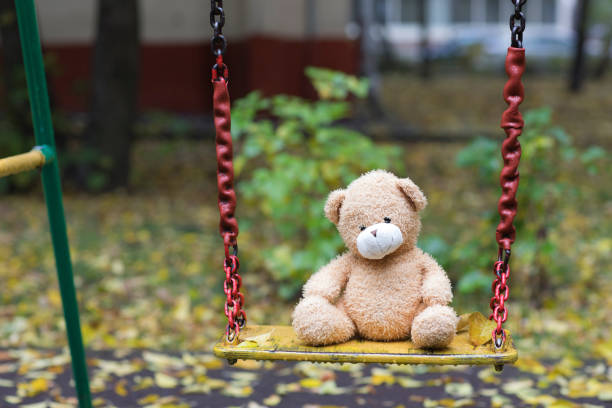 istock Brown plush teddy bear on a yellow colourful swing. 925698810