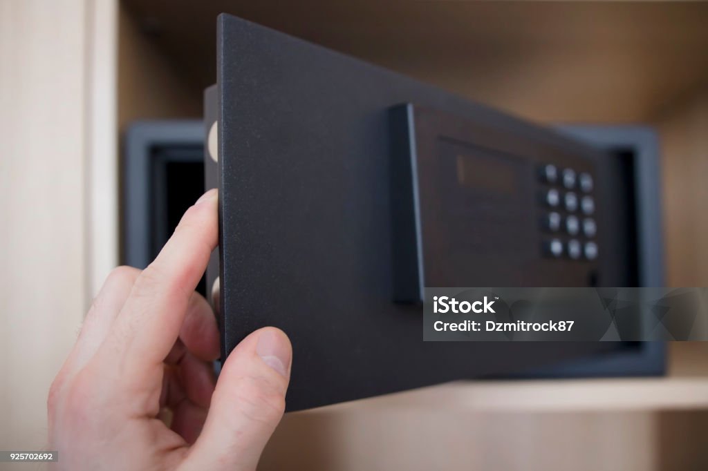 Man opens safe depository of valuables and money in his home. Keep the money in the safe at home. Safe, hand close-up. Man opens safe depository of valuables and money in his home. Keep the money in the safe at home. Safe, hand close-up Safe - Security Equipment Stock Photo