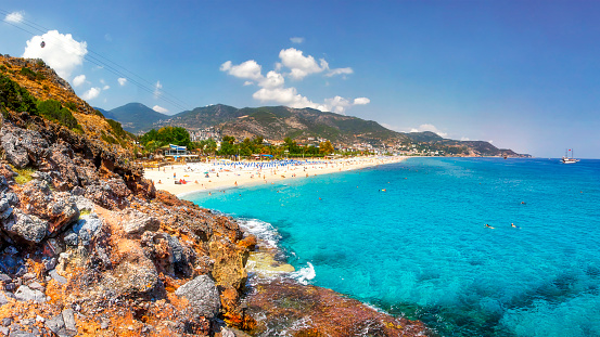 Sea landscape of the Mediterranean on clear sunny day. Sandy beach, rocks, blue sky, mountains and sea. Paradise Bay in Alanya. Tropical resort for summer holidays. coastline of sea resort beach