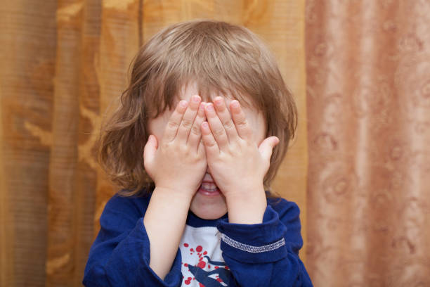 il bambino di 4 anni ha chiuso il viso con i palmi delle mani. - surprise child 4 5 years little boys foto e immagini stock