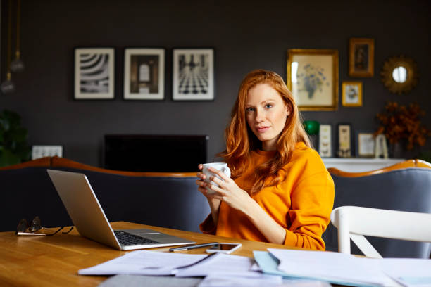 istock Woman holding coffee cup while working at home 925709902