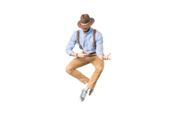 istock stylish young man in hat jumping and gesturing with hands isolated on white 925713956