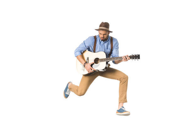 istock handsome young musician in hat playing guitar and jumping isolated on white 925714394