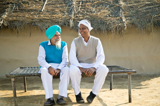 Two Indian farmers discussing on traditional bed outdoors