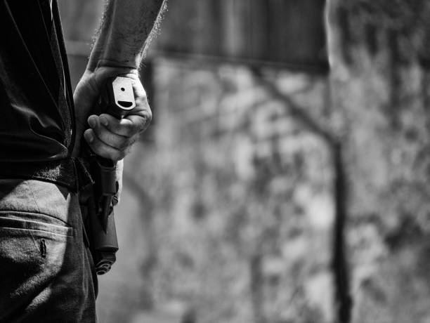 black and white image of male holding handgun in holster ready to shoot in shooting competion stock photo