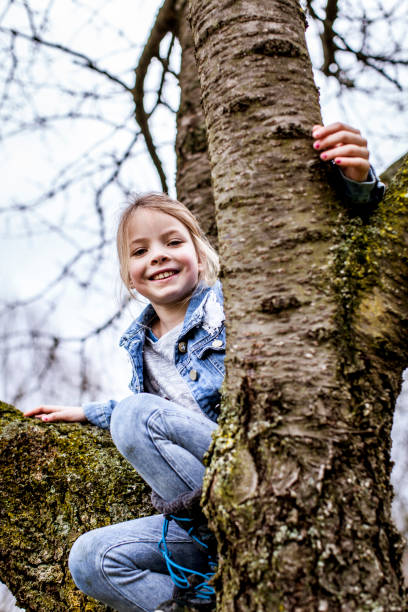 istock young, blond, beautiful girl is climbing on tree in austria 925726592