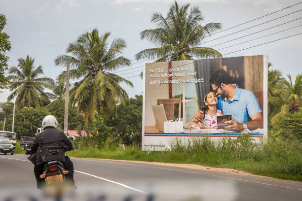 Advertisment posters along the road Anuradhapura, Sri Lanka - December 5, 2017: Man on a motorcyle passes a poster, advertising for families and the future anuradhapura photos stock pictures, royalty-free photos & images