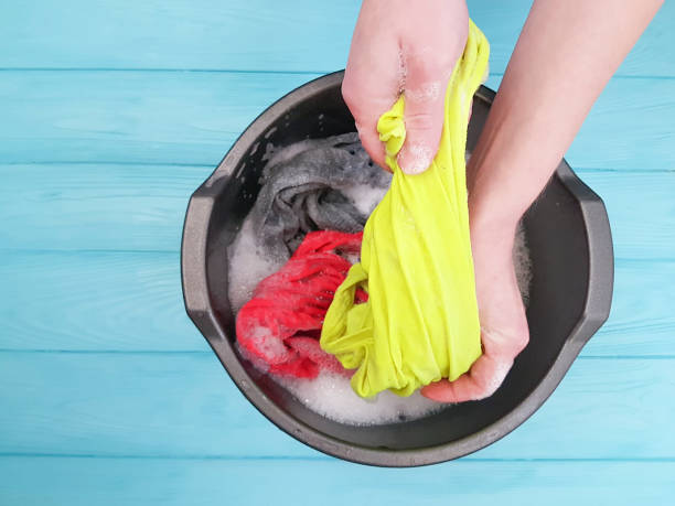 istock hands wash clothes in a basin wooden floor 925731852