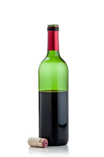 Front view of an open half full wine bottle shot on reflective white background. The bottle is green colored with a red collar. The cork is laying beside the bottle. High key DSRL studio photo taken with Canon EOS 5D Mk II and Canon EF 70-200mm f/2.8L IS II USM Telephoto Zoom Lens