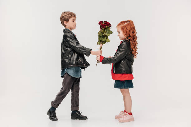 istock handsome little boy presenting roses bouquet to his girlfriend isolated on grey 925733172