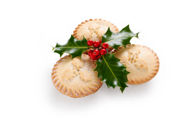 Close up of Christmas Mince Pies and holly sprig isolated on a white background
