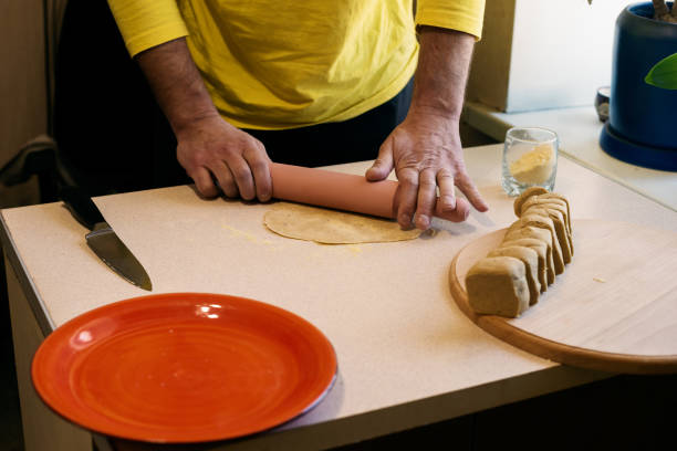 istock Male hands roll out the dough with a rolling pin on a white table 925750316