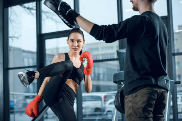 istock young female fighter performing low kick with trainer at gym 925758784