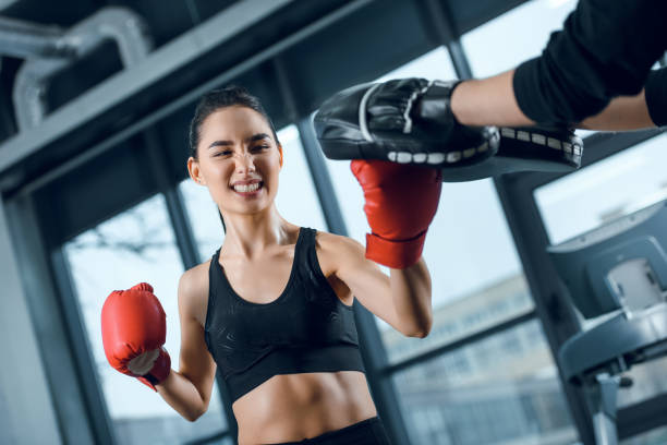 istock expressive young female boxer exercising with trainer at gym 925762776