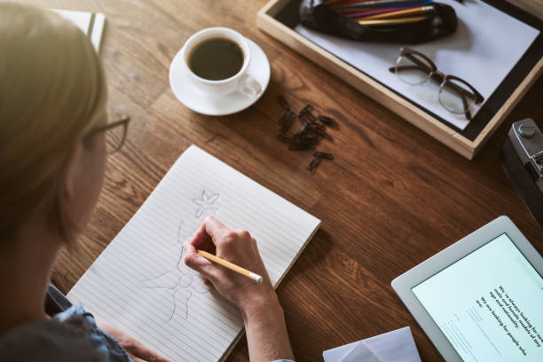 istock Woman sketching pictures in a notepad while working at home 925763230