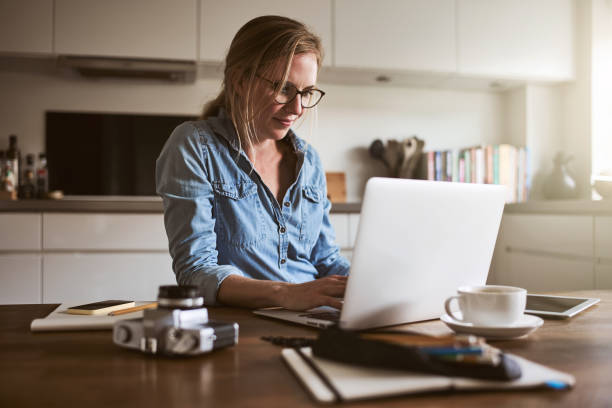 istock Young woman working online with a laptop in her kitchen 925763400