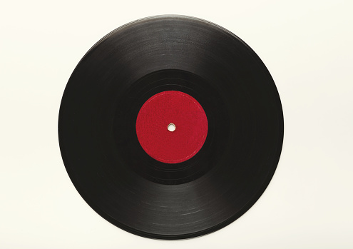 Old black vintage vinyl record with red label isolated on white background. Top view on retro media storage, copy space, cutout