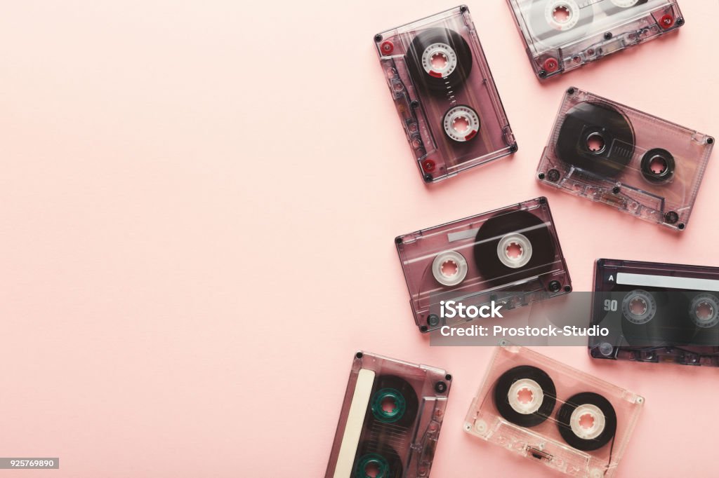 Vintage audio cassettes border on pink background Creative border of vintage cassettes. Old retro tapes on pink background, top view with copy space, multimedia concept Audio Cassette Stock Photo