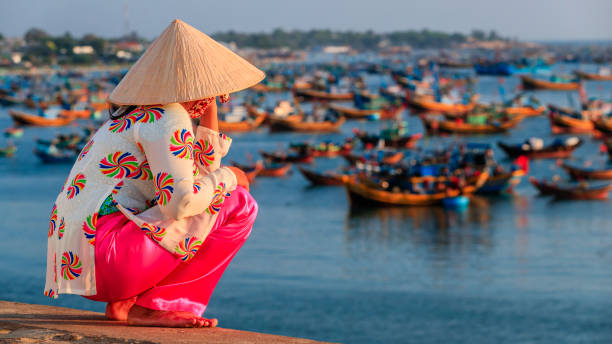 Vietnamese woman looking at fishermen's boats, Vietnam Vietnamese woman looking at fishermen's boats  in a harbour, Vietnam ao dai stock pictures, royalty-free photos & images