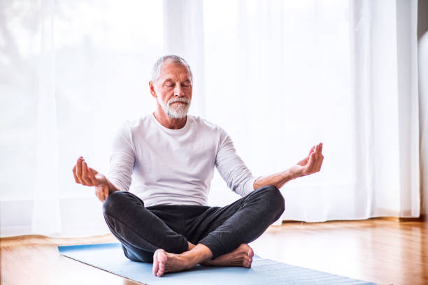 ältere mann zu hause meditieren. - senior adult sport yoga exercising stock-fotos und bilder