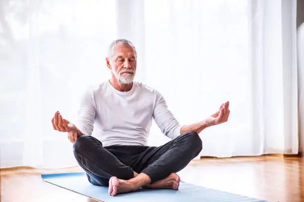 Photo of Senior man meditating at home.