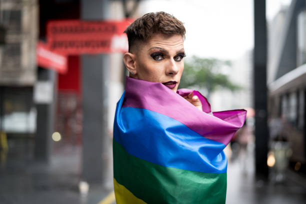 zuversichtlich gay boy mit regenbogenfahne - homosexual gay man parade flag stock-fotos und bilder