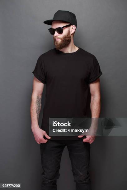 Hipster Handsome Male Model With Beard Wearing Black Blank Tshirt With Space For Your Logo Or Design Over Gray Background Stock Photo - Download Image Now