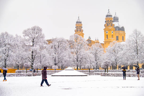 People enjoying the Odeonsplatz in Munich , Germany, during the snow storm - The Theatiner church in background