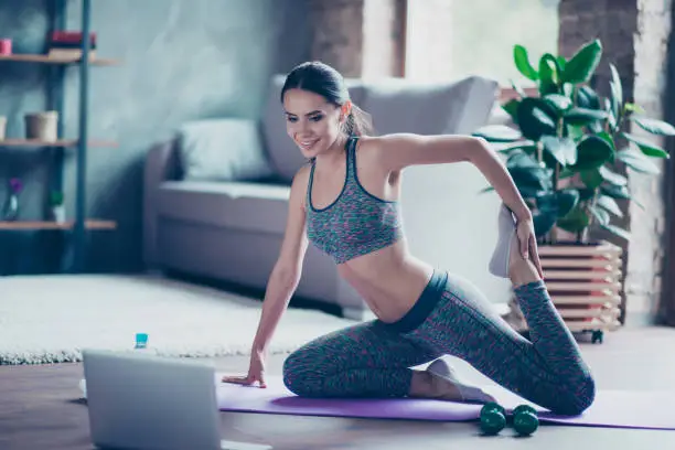 I choose healthy and sportive lifestyle! Pretty beautiful woman is stretching her legs, feet and doing exercise at home on the floor, she is watching helpful videos on the internet