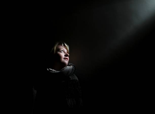 young woman in dark room looking towards light
