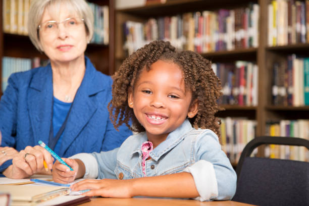 istock Teacher, mentor helps elementary-age schoolgirl with homework. 925786092