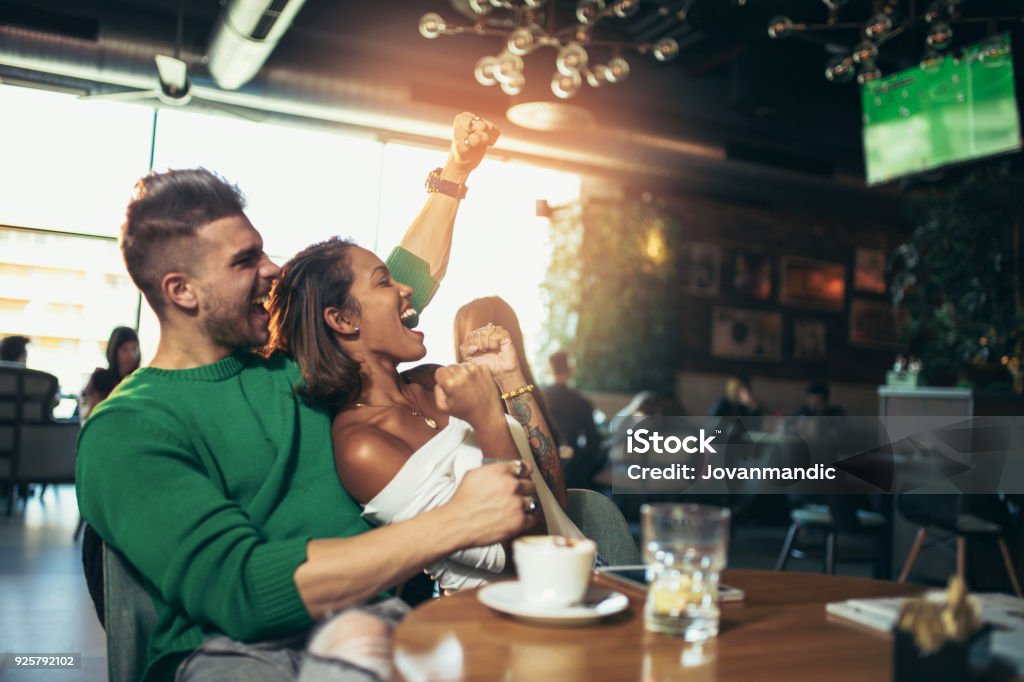 Couple heureux de célébrer tout en regardant un match de football dans un café - Photo de Bar libre de droits