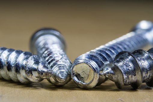 Bolts and screws for metal on a workshop table. Joinery accessories for furniture repair. Light background.