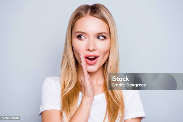 No Decir A Nadie Hablador Misteriosa Mujer Muy Hermosa Con Cabello Rubio Vestido Con La Camiseta Blanca Es Decir Secreto Caliente Noticias De Frenado Y Mirando A Un Lado Aislado En Fondo Gris Foto de stock y más banco de imágenes de Susurrar