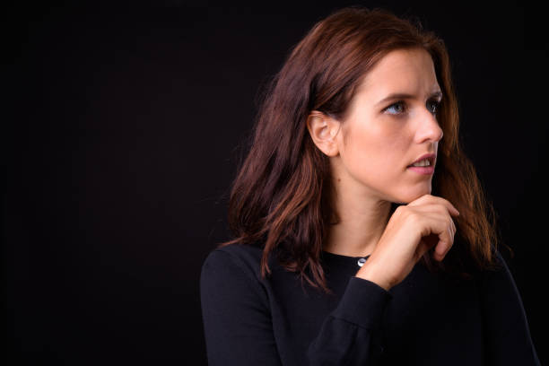 Studio shot of young beautiful woman against black background