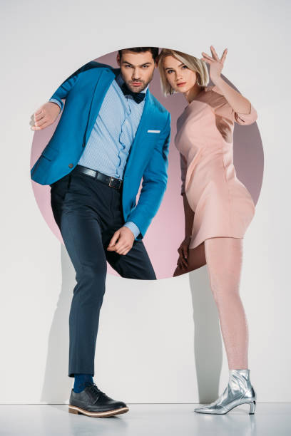 istock fashionable couple in love looking at camera while stepping through hole on grey 925810120