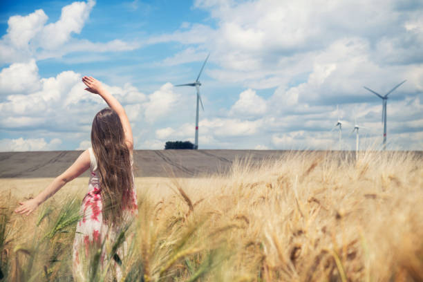 istock Girl is standing towards wind turbines 925819004