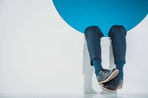 close-up partial view of stylish man falling into hole on grey