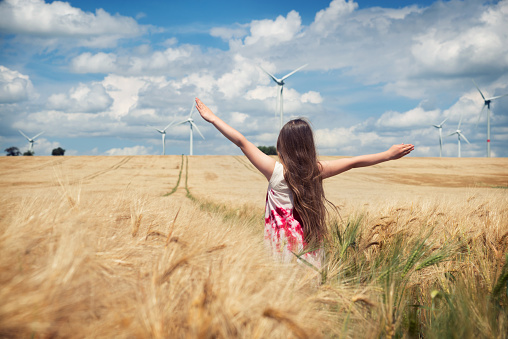 Girl is standing towards wind turbines