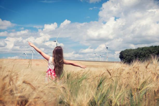 Girl is standing towards wind turbines