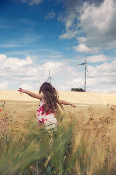 niña corre hacia las turbinas de viento - run of the mill fotografías e imágenes de stock