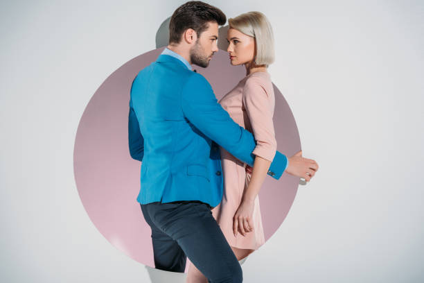 istock beautiful stylish young couple looking at each other while standing on hole on grey 925820912