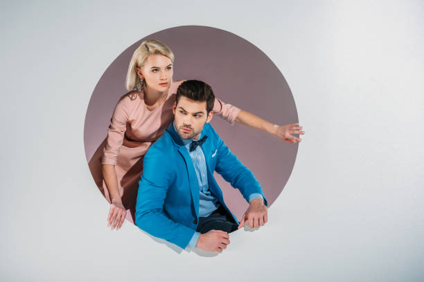 istock stylish young couple peering out hole on grey 925821084