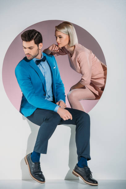 istock stylish young couple looking away while sitting together in aperture on grey 925825330