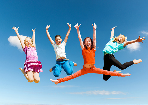 Group of happy active children jumping outdoors