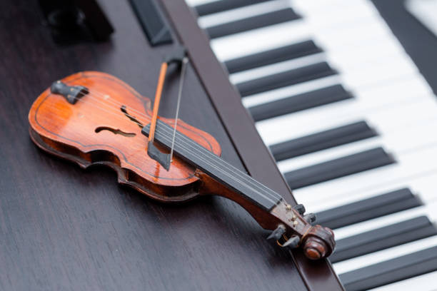 istock A miniature violine on dark wooden piano 925830618