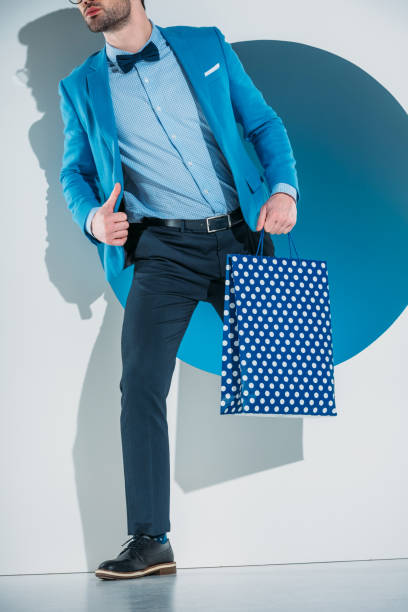 istock stylish young man with shopping bag stepping through hole on grey 925832064