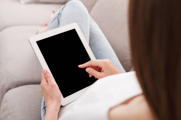 istock Unrecognizable brunette girl with tablet sitting on the sofa 925837886