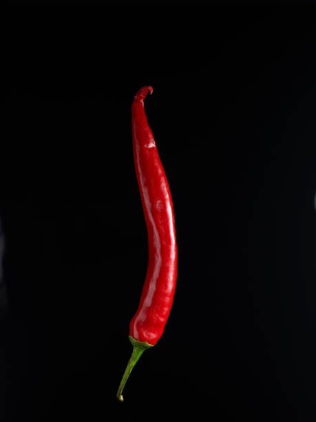 пламенный горячий перец на черном фоне - chili pepper стоковые фото и изображения